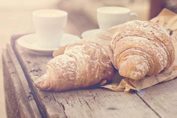 A cup of coffee "espresso" and croissant on the wooden table. Tonned photo. — Stock Photo, Image