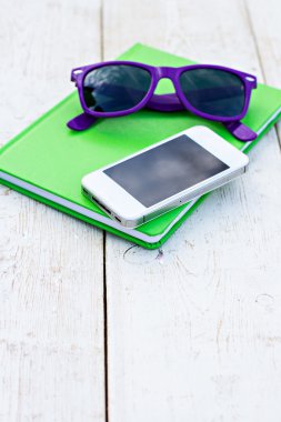 Dizüstü bilgisayar, cep telefonu ve ahşap bir masa üzerinde güneş gözlüğü