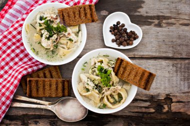 Bir kase erişte ve ahşap bir masa üzerinde tavuk çorbası
