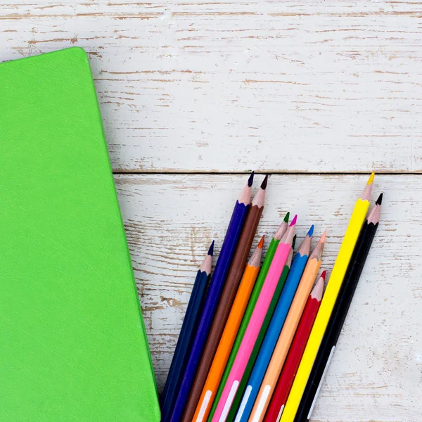 Renkli kalemler ve ahşap bir masa üstünde bir defter — Stok fotoğraf