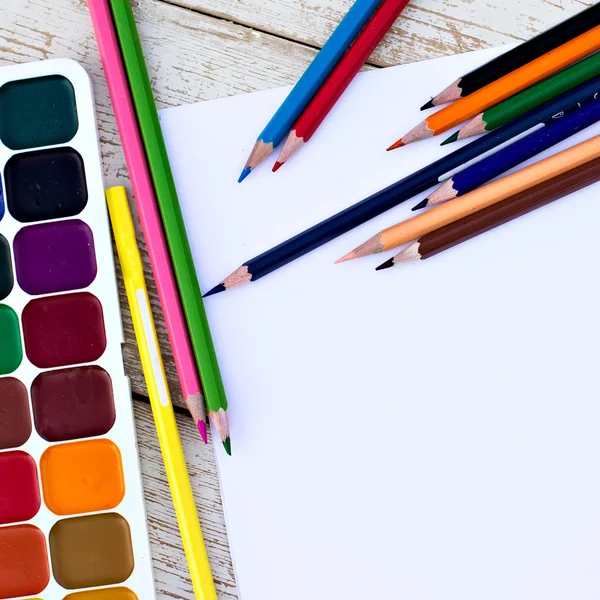 Colored pencils, water colors and paper on the desk — Stock Photo, Image