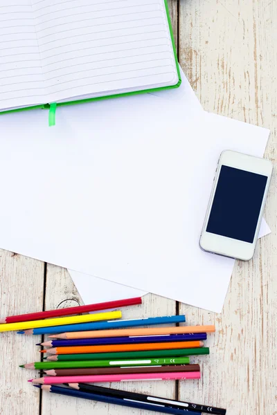 Colored pencils, cell phone and paper on the desk — Stock Photo, Image