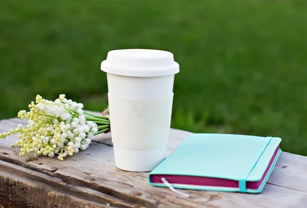 Tagebuch, ein Glas Kaffee und Maiglöckchen auf dem Tisch — Stockfoto