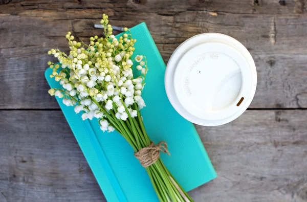 Diário, um copo de café e lírios de vale sobre a mesa — Fotografia de Stock