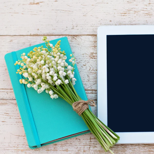 Deník, tablet počítač lilie z údolí na stůl — Stock fotografie