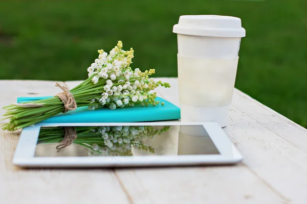 Pamiętnik, komputer typu tablet, kieliszek kawy i lilie doliny na stole — Zdjęcie stockowe