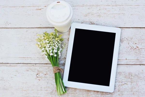 Tablet bilgisayar, bir bardak kahve ve lilyum masada Vadisi