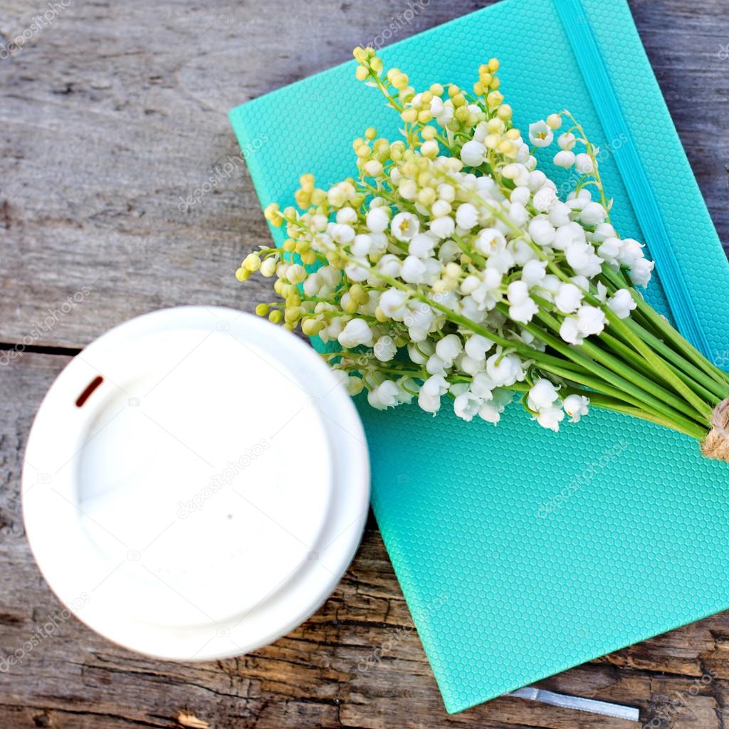 Diary, a glass of coffee and  lilies of valley  on the table