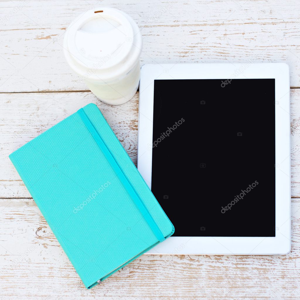 Diary, a tablet computer, a glass of coffee on the table