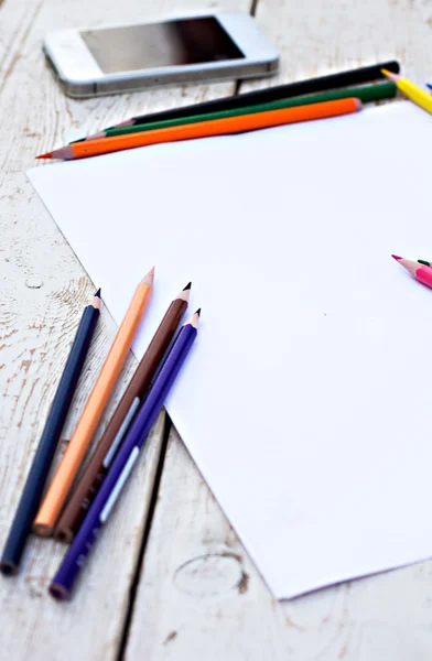 Colored pencils, cell phone and paper on the desk — Stock Photo, Image