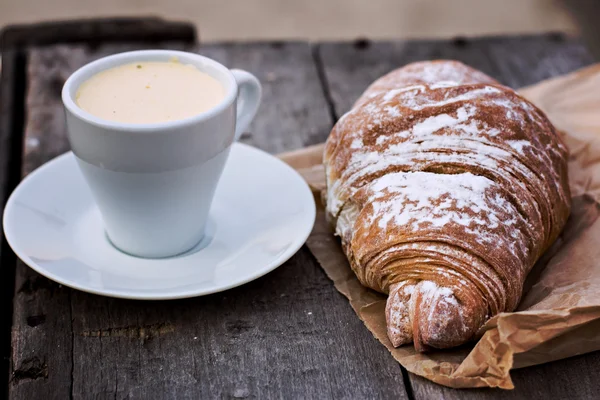 A cup of coffee "espresso" and croissant on the wooden table. Tonned photo. — Stock Photo, Image