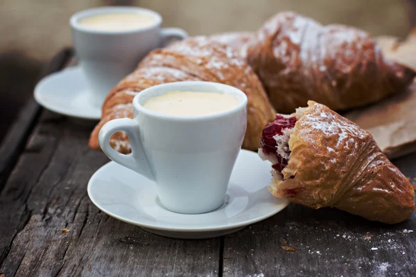 A cup of coffee "espresso" and croissant on the wooden table. Tonned photo. — Stock Photo, Image