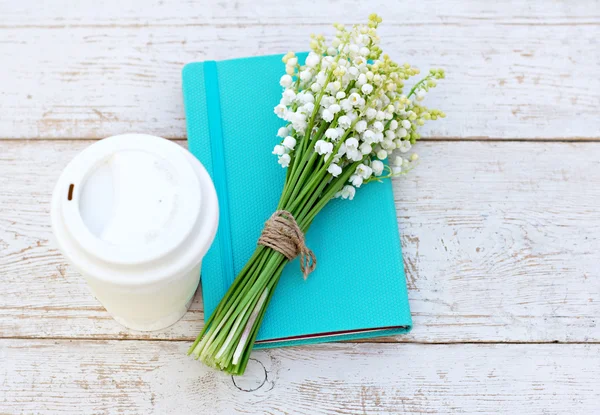 Dagboek, een glas koffie en lelies van de vallei op de tafel — Stockfoto