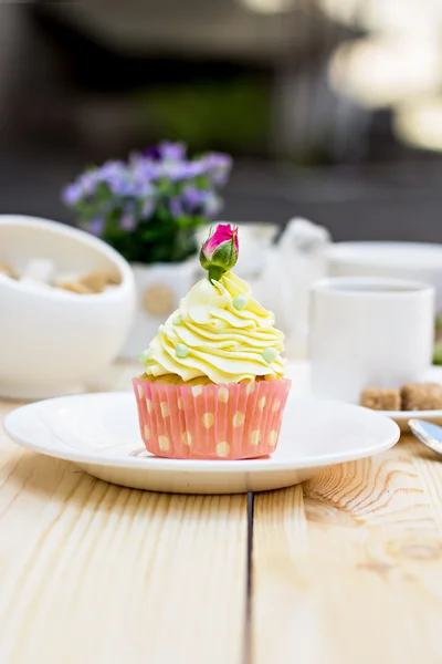 Cupcake amarillo claro con rosa sobre la mesa Imagen de stock