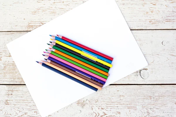 Colored pencils and a sheet of paper on the table — Stock Photo, Image