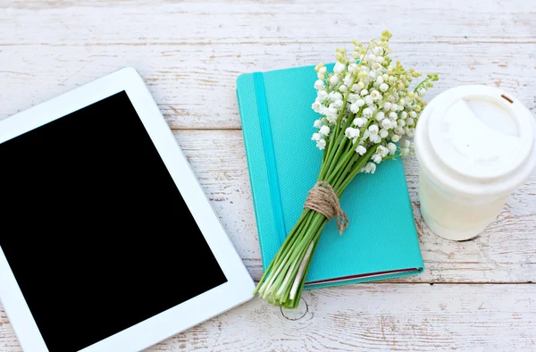 Diario, un computer tablet e gigli di valle sul tavolo — Foto Stock