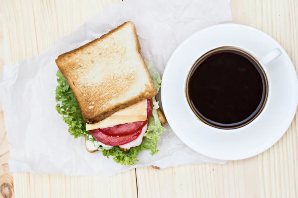 Sandwich y taza de café negro en la mesa —  Fotos de Stock