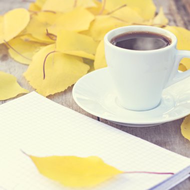 Defter, fincan kahve ve sarı sonbahar eski ahşap masa üzerinde bırakır. Tonned fotoğraf.