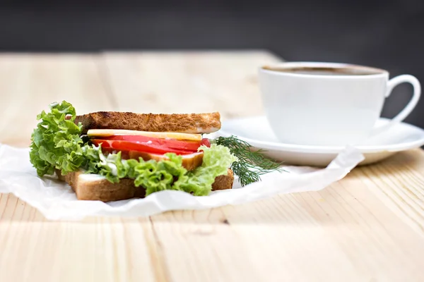 Sandwich y taza de café negro en la mesa — Foto de Stock
