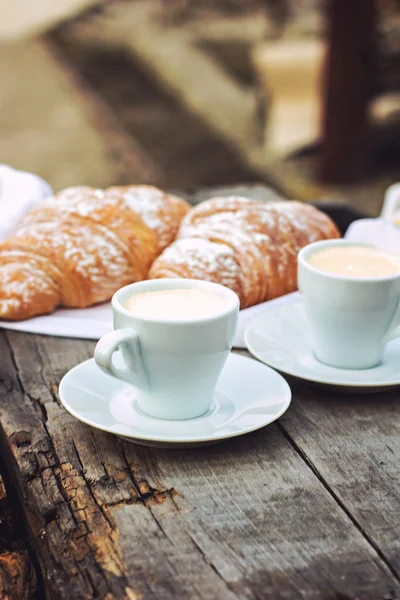 Een kopje koffie "espresso" en croissant op houten tafel. Tonned foto. — Stockfoto