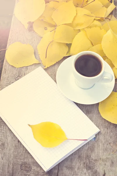 Caderno, xícara de café e folhas de outono amarelas — Fotografia de Stock