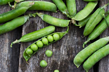 Ahşap arka plan üzerinde genç taze yeşil bezelye