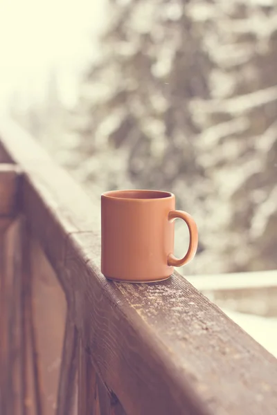 Una taza con una bebida caliente en el fondo del bosque de invierno — Foto de Stock