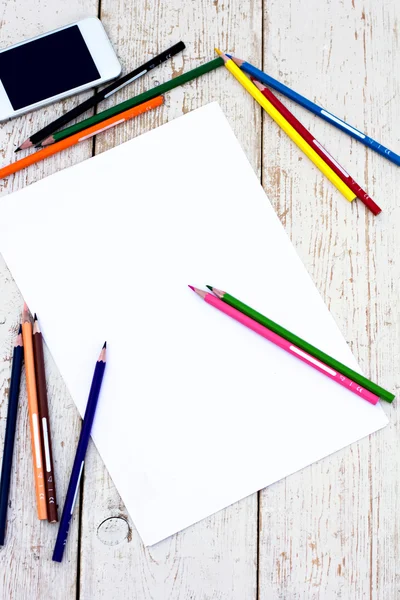 Colored pencils, cell phone and paper on the desk — Stock Photo, Image