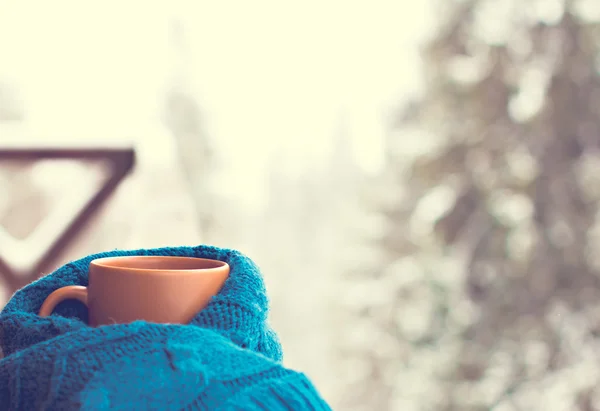 Una taza con una bebida caliente en el fondo del bosque de invierno — Foto de Stock