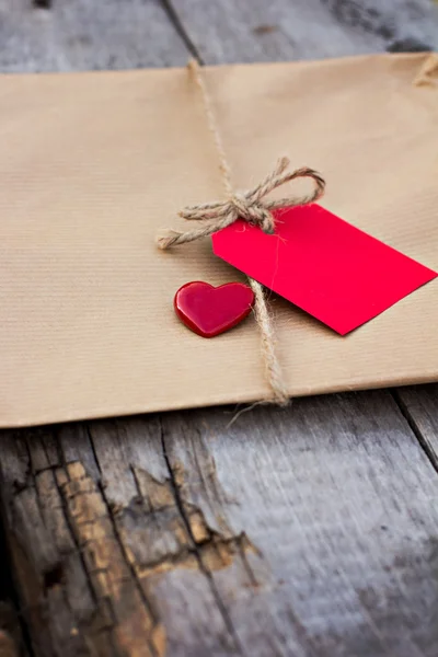 Gift in kraft paper with red card — Stock Photo, Image