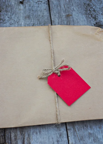 Gift in kraft paper with red card — Stock Photo, Image