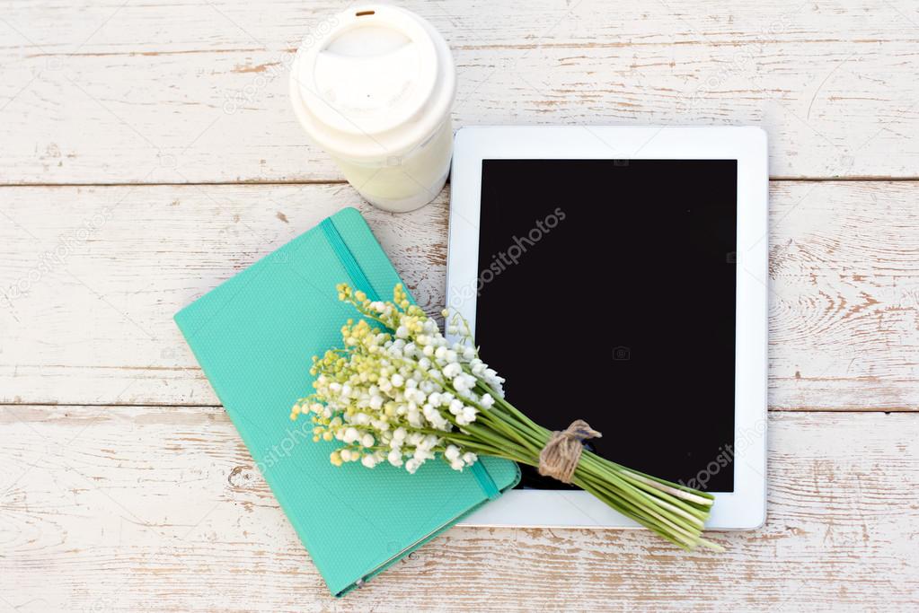 diary, a tablet computerand  lilies of valley