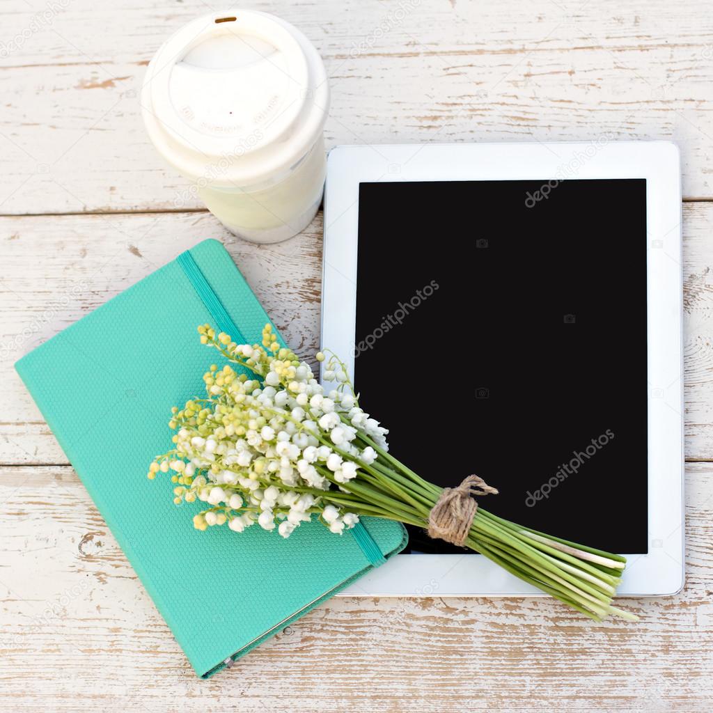 diary, a tablet computerand  lilies of valley