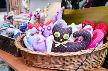 Kumaş kedi bebekleri sepette yatıyor. Bir sokak pazarında satılan hediyelik eşya. Bir sürü renkli el işi oyuncağı.