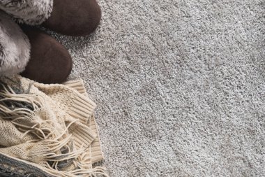 Sıcak kış arkaplanı, bej renkli kalın giysiler. İskandinav tarzı süveter, atkı ve terlikler. Düz yatış, üst görünüm