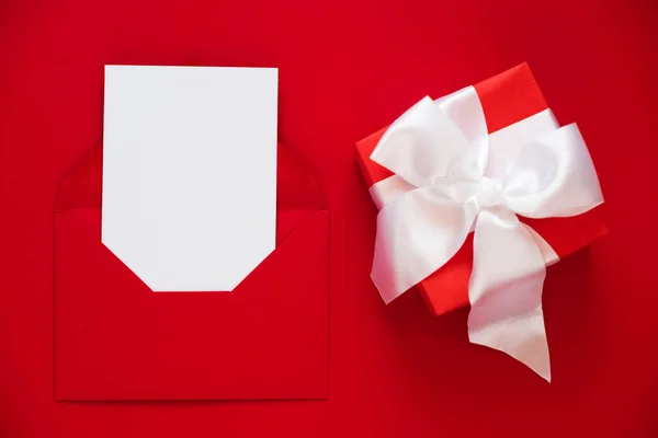 Mockup de cartão de saudação no envelope e presente no fundo vermelho. Feliz Dia dos Namorados ou das Mães. — Fotografia de Stock