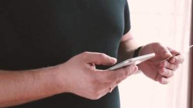 Kredi kartı ve akıllı telefonla alışveriş yapan bir adam. Eller yukarı..
