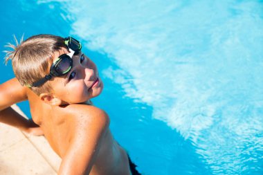 Yüzme havuzunda gözlüklü mutlu çocuğun aktif yaşam tarzı yaz tatili konsepti
