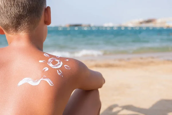 Sluneční krém v podobě slunce a vlny na kůži chlapce letní slunečný den pro cestování — Stock fotografie