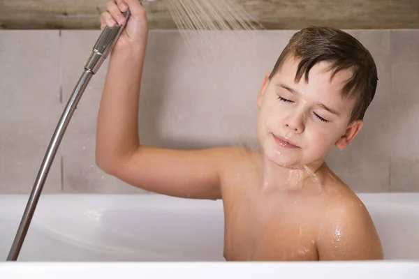 Chłopiec trzyma prysznic i myje głowę w łazience zdrowe dzieciństwo — Zdjęcie stockowe