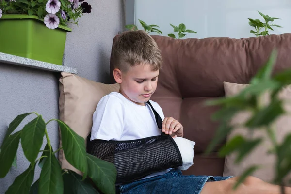 Ein Junge richtet eine Armschlinge auf einem gebrochenen Arm auf — Stockfoto