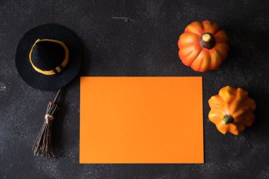 Cadılar Bayramı tebrik kartı, balkabakları ve karanlık arka planda dekoratif cadı özellikleri..