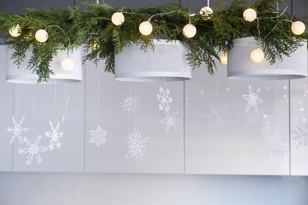 Decorazione d'interni di Natale. Fiocchi di neve lavorati a maglia bianchi, rami di abete e luci di Natale su un lampadario a bracci — Foto Stock
