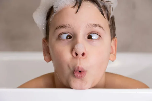 Zbliżenie portret zabawnego chłopca bawiącego się wodą i pianką w łazience — Zdjęcie stockowe
