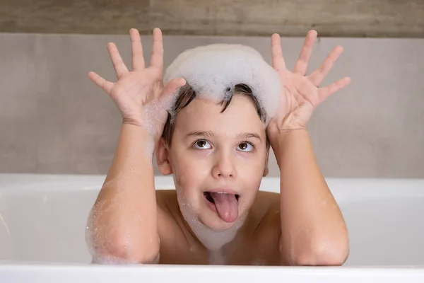 Zbliżenie portret zabawnego chłopca bawiącego się wodą i pianką w łazience — Zdjęcie stockowe