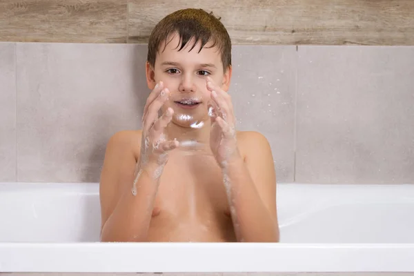 Portrait of boy playing with with soap shampoo or gel in bathroom Child bathe and inflates soap bubbles — Stock Photo, Image
