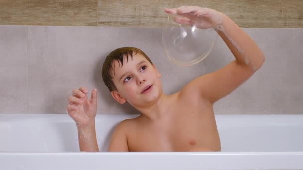 Junge spielt im Badezimmer Kind badet und bläst Seifenblasen auf — Stockvideo