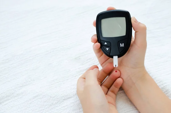 Teste de diabetes. Mãos de criança verificando o nível de açúcar no sangue por medidor de glicose. — Fotografia de Stock