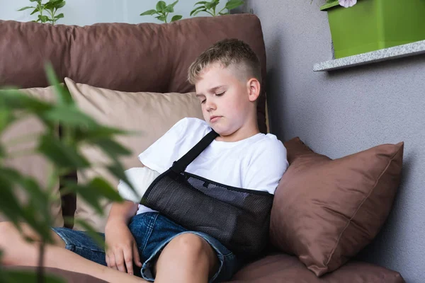 Trauriger Junge mit gebrochenem Arm im Gips langweilt sich zu Hause — Stockfoto