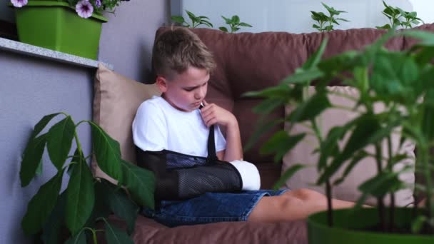 Un niño endereza un cabestrillo en un brazo roto — Vídeo de stock